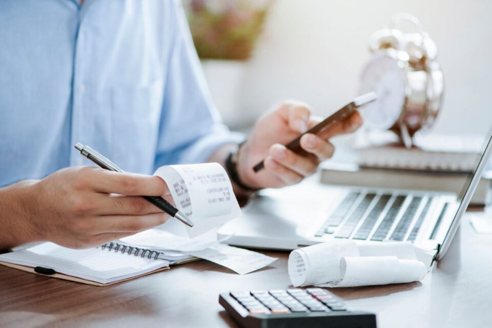 Young man holding pen with bills working for calculating taxes