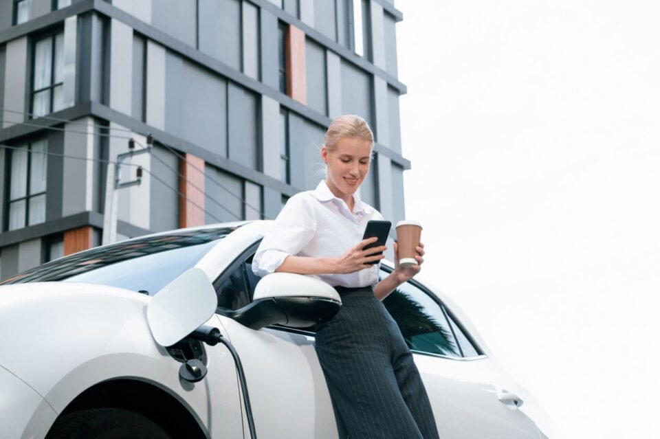 Woman charging her electric vehicle outside of a condo building