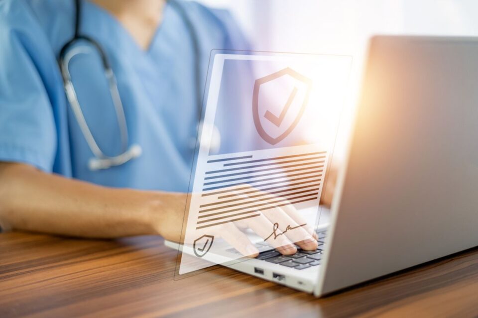 Medical professional typing on a computer displaying a privacy symbol.
