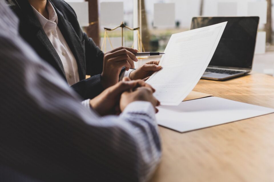 Female lawyer is explaining the terms of the legal contract document and asking the client to sign it properly. stock photo